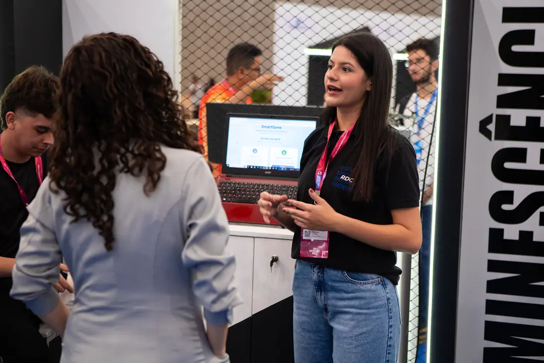 Duas pessoas conversando diante de uma demonstração em um estande do evento